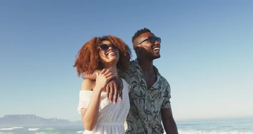 African American couple walking side by side at beach