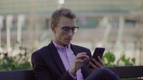 Man Using Smartphone While Sitting on Park Bench