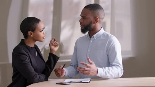 Zwei Geschäftskollegen kommunizieren über Dokumentenpapier im Büro am afrikanischen Tisch