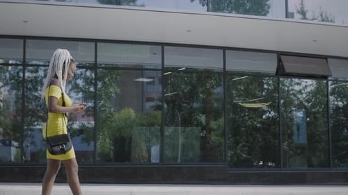 Stylish Woman Walking with Smartphone in City