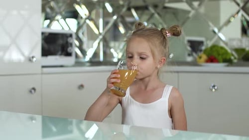Little Girl Drinks Juice in Bright Kitchen