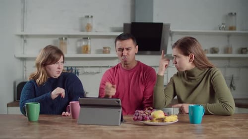 Adults Communicate Using Sign Language At Kitchen Table
