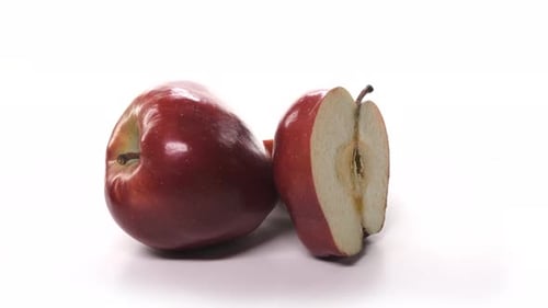 Two Cut Fresh Red Apples are Spinning on White Background
