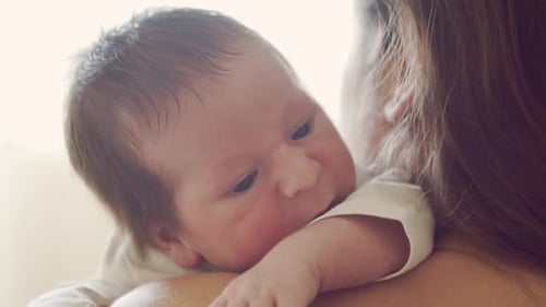 Newborn baby boy and his mother at home. Close-up portrait of the infant
