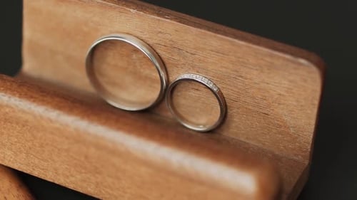 Two Wedding Rings in White Gold on Brown Wooden Stand