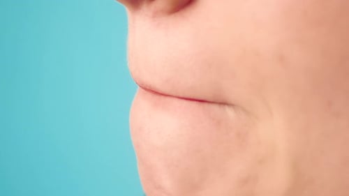 Applying Red Lipstick in Macro on Blue Background