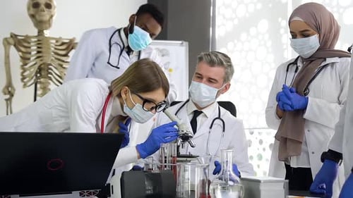 Wissenschaftlicher Arzt schaut ins Mikroskop und analysiert gemeinsam Testversuche mit Medikamenten
