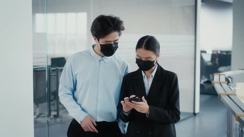 Chinese Colleagues Using Cellphone Wearing Face Masks Walking In Office