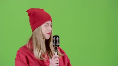Girl in Stylish Clothes Sings in a Retro Microphone Hit Songs. Green Screen