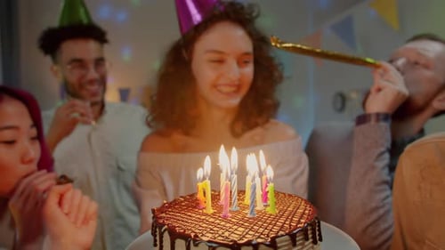 Woman Blows Out Candles at Birthday Party