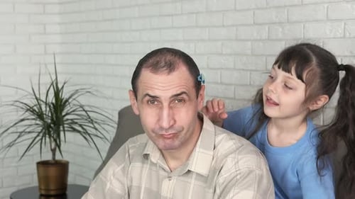 Child Affectionately Placing Hair Clips in Father's Hair