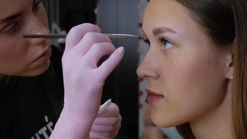 Woman Getting Eyebrows Styled by Makeup Artist