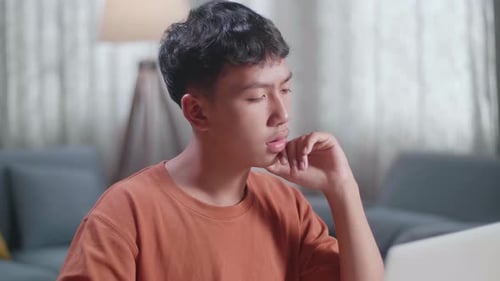 Close Up Of Asian Boy Footwear Designer Thinking While Working On A Laptop At Home