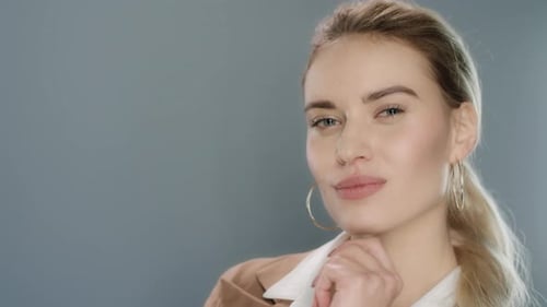 Sensual Woman Posing and Winking To Camera in Gray Studio Background