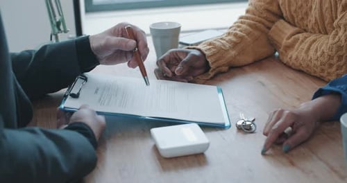 Close up of hands of mature agent discussing contract with two clients