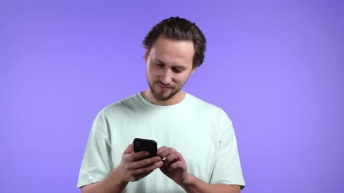 Handsome Man Using Smartphone on Violet Studio Wall
