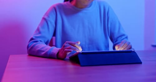 Young Adult Using Tablet at Night with Neon Lighting