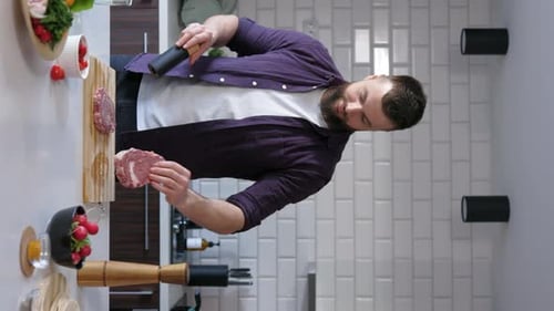 Bearded Man Seasoning Meat in Modern Kitchen