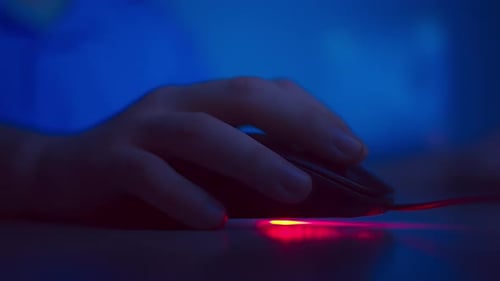 Nahaufnahme der Hand eines Mannes, der die Tasten einer Computermaus drückt, Abendlicht