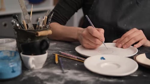 Potter Designs Ceramics with Fine Paintbrush
