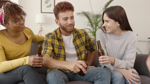 Friends Toasting Beers on Living Room Couch