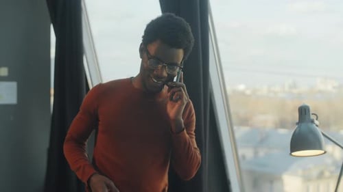 Black Man Talking on Phone and Working on Laptop in Office