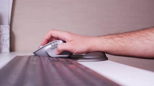 A Man Works at a Computer Using a Wireless Mouse