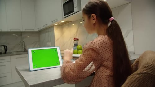Rear View of School Girl Doing Homework Online Using Tablet Indoors