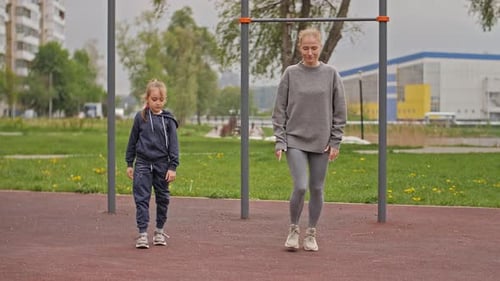 Slow Motion Mother and Daughter Doing Exercises on Open Air Sport Playground. Sportive Family