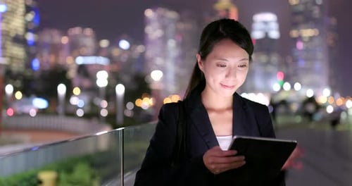 Woman Uses Tablet in the City at Night
