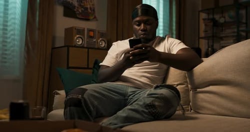 Young Man Relaxing at Home Using Mobile Phone