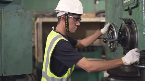Factory worker controlling machine in the industrial construction
