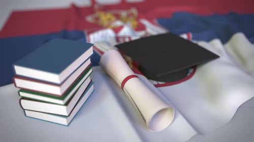Abschlusskappe und Diplom auf der Flagge Serbiens