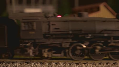 Closeup da locomotiva de brinquedo com vagões em movimento na ferrovia.