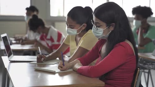 Secondary School Students Wearing Medical Face Masks Writing Notes During Class at the High School