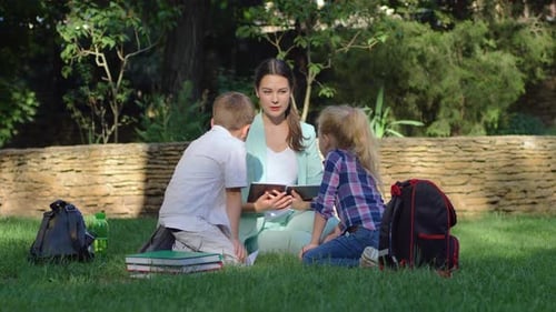 Primary School, Little Schoolboy and Schoolgirl with Teacher Woman Read Textbook and Chat During