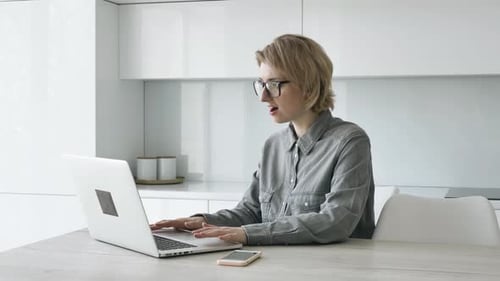 Woman Works on Laptop in Bright Modern Kitchen