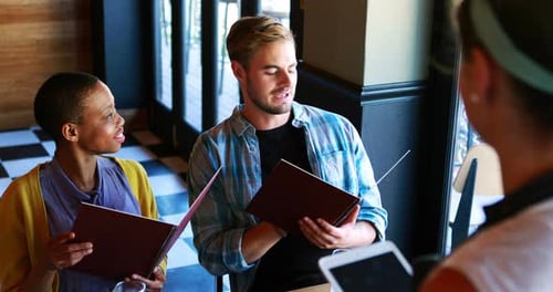 Customers Ordering Food from Waitress at Restaurant Table