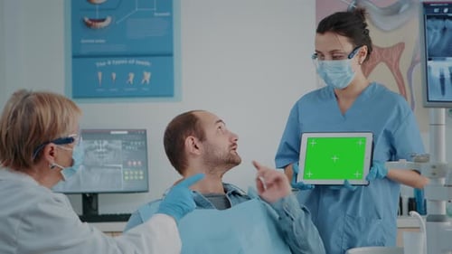 Patient and Dentistry Team Looking at Tablet with Green Screen