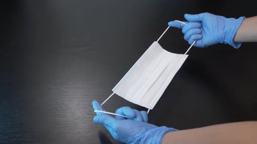 Hands with Gloves Hold Surgical Mask
