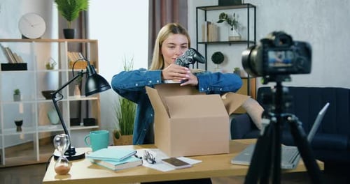 Bloguera rubia graba un proceso de desempaque en un estudio doméstico y mostraba un nuevo mando