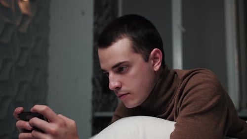 Close Up Caucasian Man Playing Game on Phone and Looking Concentrated. Handsome Man Holding Phone