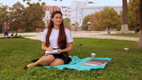 Woman Writing in Notebook, Sitting on Green Lawn