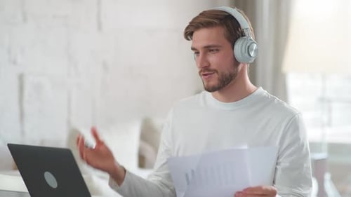 Man Attends Online Meeting With Laptop and Headphones