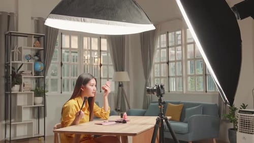 Mujer bloguera de belleza grabando un tutorial diario de rutina de maquillaje ante la cámara, influencer