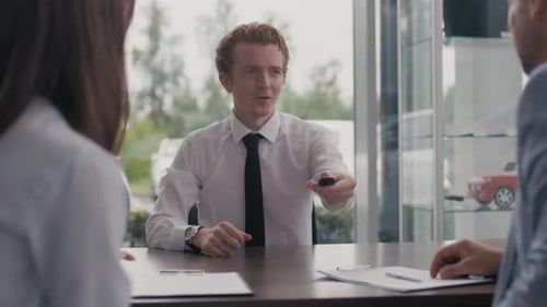 Salesman Handing Keys to New Car Owners