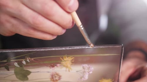 Applying Glue to Framed Pressed Flowers Artwork
