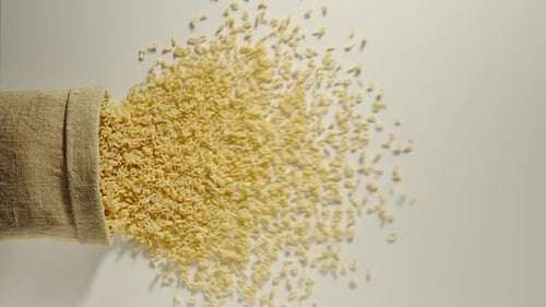 Bag falls and pasta letters are poured out of it on white background