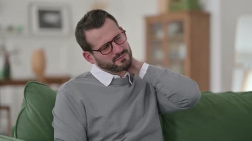 Man Rubs Stiff Neck on Couch