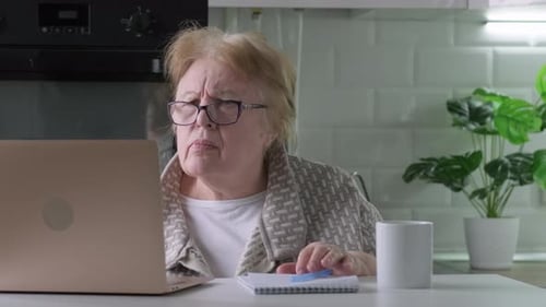 Worried Senior Woman at Home Looking at Laptop Seeing Bad News